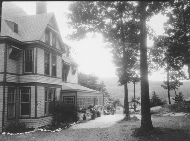 Victorian-era house surrounded by trees and gardens, showcasing detailed architecture and scenic landscape, relevant for historical context.